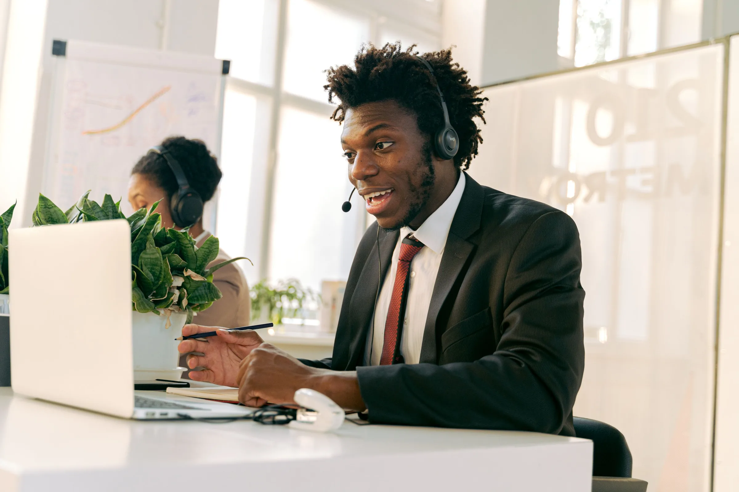 A smiling customer support agent on a headset in a bright office